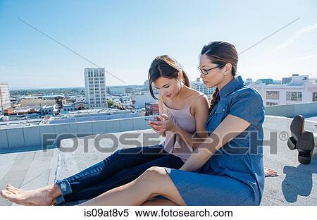 Businesswomen using smartphone on roof terrace, Los Angeles, California, USA View Large Photo Image Stock Photography - Businesswomen using smartphone on roof terrace, Los Angeles, California, USA. Fotosearch
