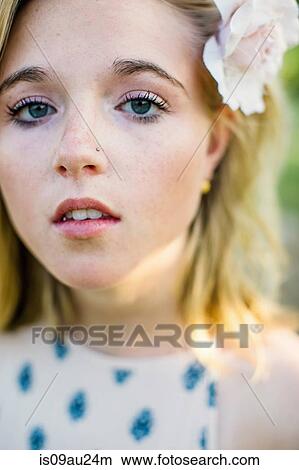 Close up portrait of young woman with nose stud, flower in hair looking at camera View Large Photo Image Picture - Close up portrait of young woman with nose stud, flower in hair looking at camera. Fotosearch