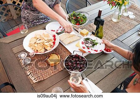 Cropped overhead view of two female friends eating lunch on patio View Large Photo Image Stock Image - Cropped overhead view of two female friends eating lunch on patio. Fotosearch