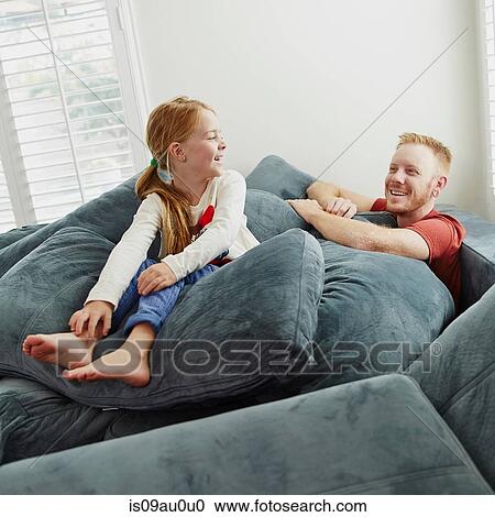 Father and daughter playing on pile of cushions in living room View Large Photo Image Stock Image - Father and daughter playing on pile of cushions in living room. Fotosearch