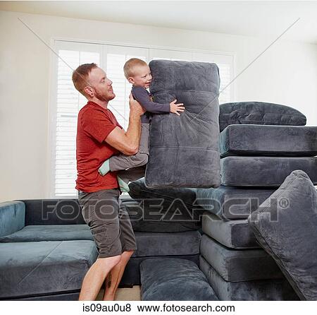 Father and son stacking cushions in living room View Large Photo Image Stock Photo - Father and son stacking cushions in living room. Fotosearch