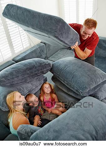 Father covering family sitting among cushions in living room View Large Photo Image Stock Photo - Father covering family sitting among cushions in living room. Fotosearch