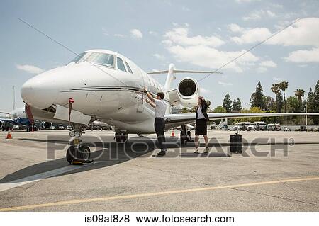 Stock Photo - Female businesswoman preparing to travel in private jet at airport. Fotosearch