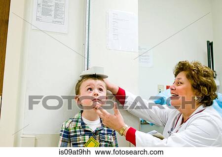 Stock Image - Female doctor checking height of young boy. Fotosearch