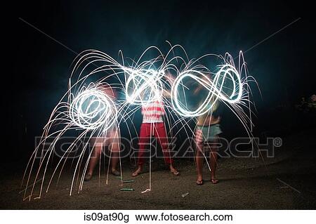 Stock Image - Four adult friends making sparkler patterns in darkness on Independence Day, USA. Fotosearch