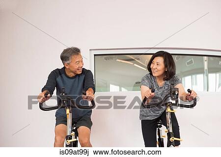 Front view of mature couple using exercise bikes face to face smiling View Large Photo Image Stock Image - Front view of mature couple using exercise bikes face to face smiling. Fotosearch