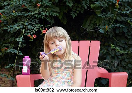 Stock Image - Girl blowing bubbles in garden. Fotosearch