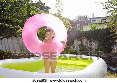 Stock Image - Girl holding up inflatable in pool. Fotosearch