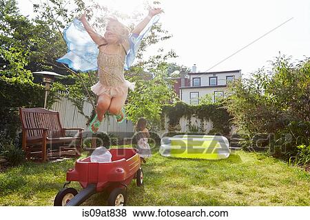 Stock Photo - Girl in butterfly costume jumping up from toy wagon. Fotosearch