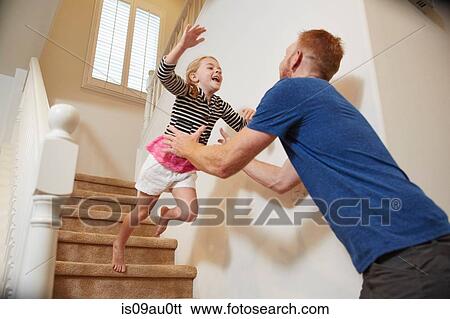 Girl jumps into father's arms on staircase at home View Large Photo Image Stock Photograph - Girl jumps into father's arms on staircase at home. Fotosearch