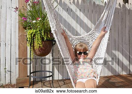 Stock Photo - Girl lying in hammock on porch. Fotosearch