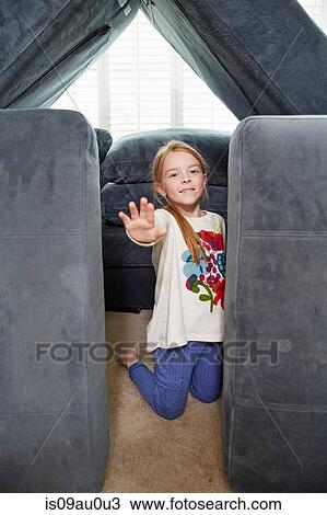 Stock Image - Girl stopping entry into tower of cushions in living room. Fotosearch