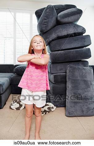 Girl with arms crossed in living room, pile of cushions in background View Large Photo Image Stock Image - Girl with arms crossed in living room, pile of cushions in background. Fotosearch