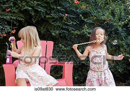 Girls blowing bubbles in garden View Large Photo Image Stock Image - Girls blowing bubbles in garden. Fotosearch