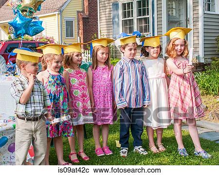 Stock Image - Group of children at kindergarten graduation, wearing paper mortar boards. Fotosearch