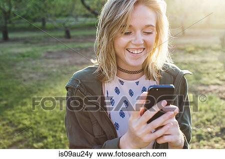 Head and shoulders of young woman using smartphone looking down smiling View Large Photo Image Stock Photo - Head and shoulders of young woman using smartphone looking down smiling. Fotosearch