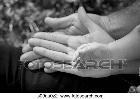 Stock Image - High angle view of mother, father and sons hands, black and white. Fotosearch