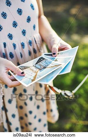Stock Image - High angle view of young woman holding photographs. Fotosearch