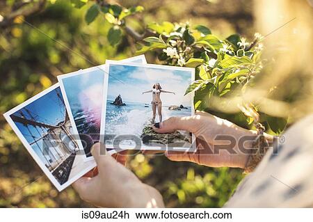 Stock Image - High angle view over shoulder of young woman holding photographs. Fotosearch
