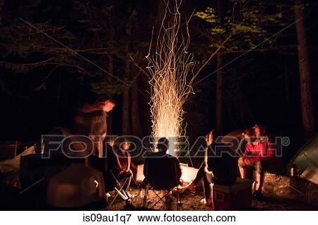 Hiker relaxing around bonfire at night View Large Photo Image Stock Photo - Hiker relaxing around bonfire at night. Fotosearch