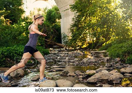 Stock Image - Jogger crossing stream under arch bridge, Arroyo Seco Park, Pasadena, California, USA. Fotosearch