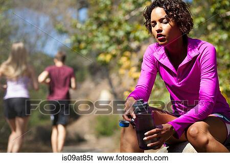 Stock Photograph - Jogger taking break in park. Fotosearch
