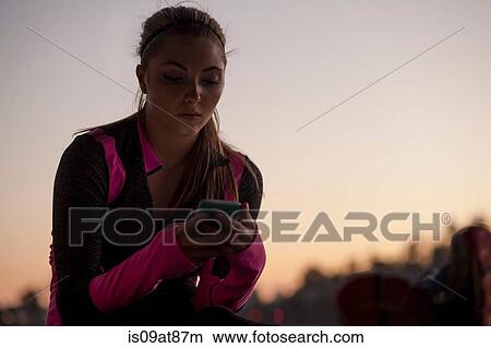 Picture - Jogger using cellular phone. Fotosearch