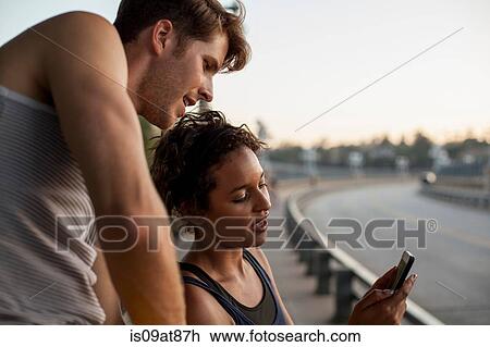 Stock Image - Joggers using cellular phone on bridge, Arroyo Seco Park, Pasadena, California, USA. Fotosearch