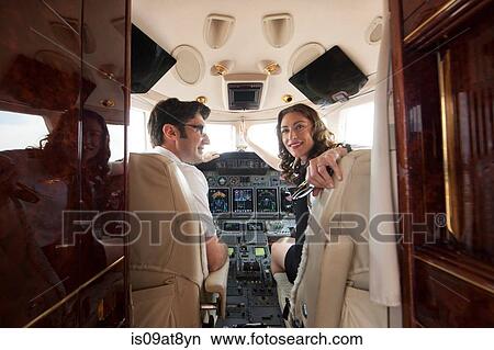 Male and female pilot looking over her shoulder in cockpit of private jet View Large Photo Image Picture - Male and female pilot looking over her shoulder in cockpit of private jet. Fotosearch