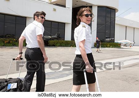 Male and female pilots pulling wheeled suitcases at airport View Large Photo Image Stock Image - Male and female pilots pulling wheeled suitcases at airport. Fotosearch