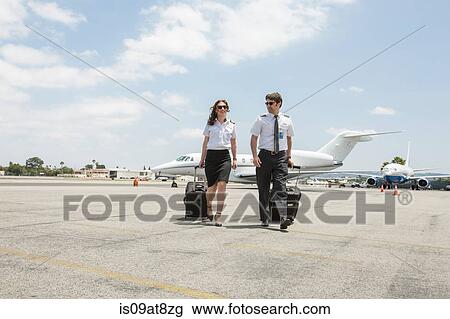 Male and female private jet pilots pulling wheeled suitcases at airport View Large Photo Image Stock Image - Male and female private jet pilots pulling wheeled suitcases at airport. Fotosearch