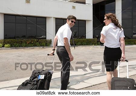 Male and female private jet pilots pulling wheeled suitcases at airport View Large Photo Image Stock Image - Male and female private jet pilots pulling wheeled suitcases at airport. Fotosearch