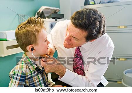Male doctor letting young boy play with stethoscope in doctor's office View Large Photo Image Picture - Male doctor letting young boy play with stethoscope in doctor's office. Fotosearch