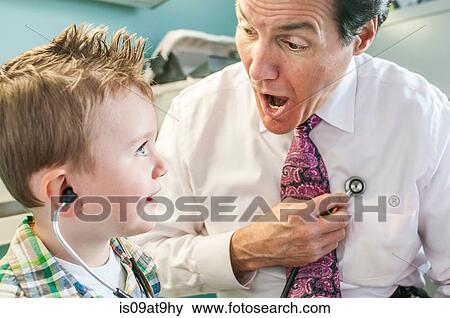 Male doctor letting young boy play with stethoscope in doctor's office View Large Photo Image Stock Photo - Male doctor letting young boy play with stethoscope in doctor's office. Fotosearch
