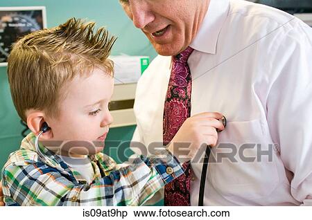 Stock Photography - Male doctor letting young boy play with stethoscope in doctor's office. Fotosearch