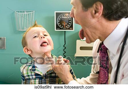Male doctor looking at young boy's tongue View Large Photo Image Stock Image - Male doctor looking at young boy's tongue. Fotosearch