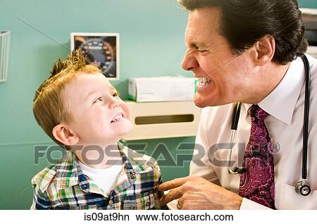 Picture - Male doctor looking at young boy's teeth. Fotosearch