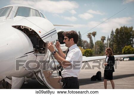 Male pilot checking private jet at airport View Large Photo Image Stock Photograph - Male pilot checking private jet at airport. Fotosearch