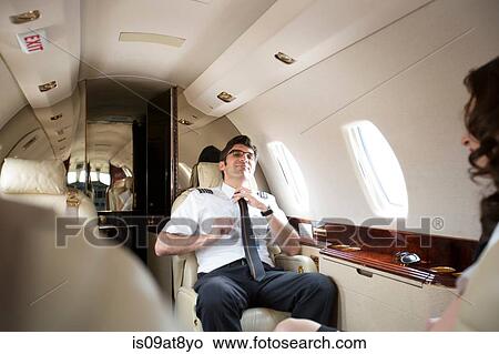 Male pilot loosening tie in cabin of private jet View Large Photo Image Picture - Male pilot loosening tie in cabin of private jet. Fotosearch