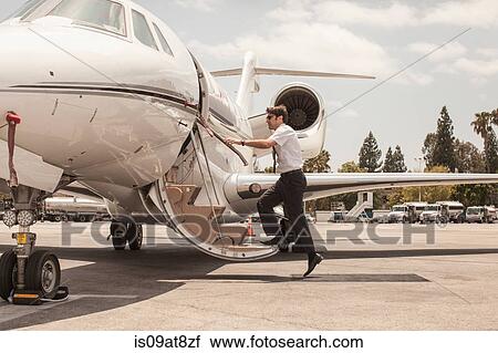 Stock Image - Male private jet pilot boarding plane at airport. Fotosearch