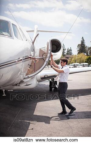 Male private jet pilot closing plane door at airport View Large Photo Image Picture - Male private jet pilot closing plane door at airport. Fotosearch