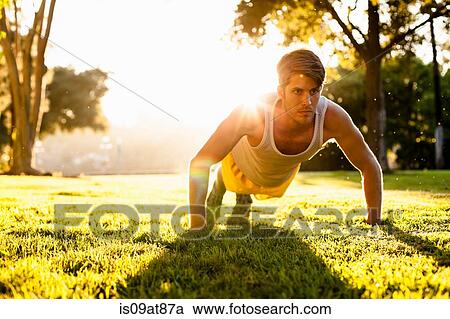 Stock Image - Man doing push ups in park. Fotosearch