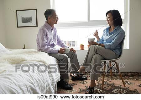 Mature couple sitting holding teacups face to face talking View Large Photo Image Stock Image - Mature couple sitting holding teacups face to face talking. Fotosearch