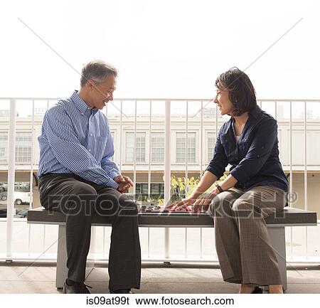 Mature couple sitting on bench face to face playing draughts View Large Photo Image Stock Photograph - Mature couple sitting on bench face to face playing draughts. Fotosearch