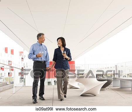 Mature couple standing holding hands and wine glasses face to face smiling View Large Photo Image Stock Image - Mature couple standing holding hands and wine glasses face to face smiling. Fotosearch