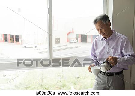 Mature man standing in front of window pouring hot water into teacup View Large Photo Image Stock Photograph - Mature man standing in front of window pouring hot water into teacup. Fotosearch