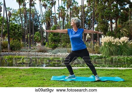 Stock Photo - Mature woman doing yoga in park. Fotosearch