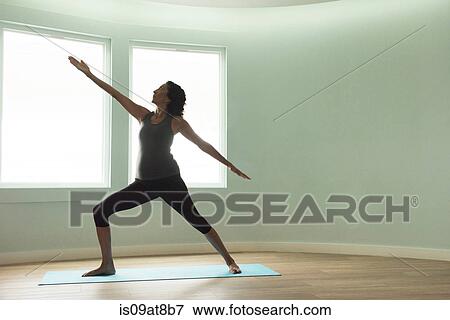 Mature woman doing yoga warrior pose in curved room View Large Photo Image Stock Photo - Mature woman doing yoga warrior pose in curved room. Fotosearch