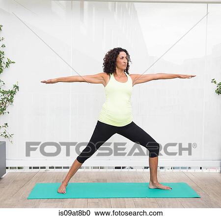 Stock Image - Mature woman doing yoga warrior pose. Fotosearch