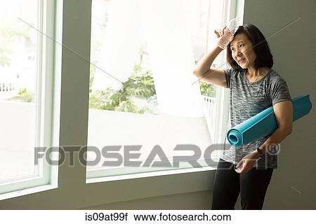 Mature woman holding bottle of water to forehead looking away View Large Photo Image Stock Image - Mature woman holding bottle of water to forehead looking away. Fotosearch